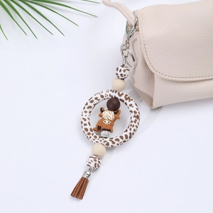 Detail of cow print silicone keychain with cartoon calf figure and brown tassel charm