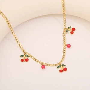 Détail d'un collier chaîne Figaro dorée avec pendentifs cerises rouges et petites perles