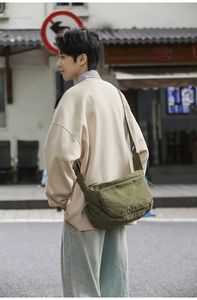 Army green nylon messenger bag showing a crossbody fit on a casual street style outfit