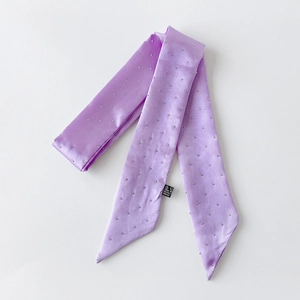 Detail eines lila Satin-Twilly-Schals mit silbernen Perlenverzierungen und seidiger Textur