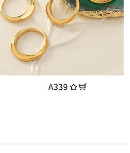 Detailed view of three gold irregular rings set on a white ceramic tray and green agate