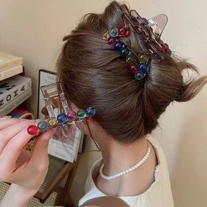 Detail view of transparent brown hair claw clip with colorful acrylic beads and spring