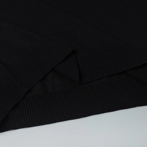 Gros plan sur la texture de la maille noire et l'ourlet large à côtes d'un haut à manches courtes