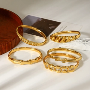 Close-up of five 18k gold plated stainless steel bracelets with various textured designs