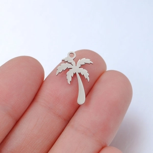 Close-up of a tiny mirror-finish stainless steel coconut tree pendant on a finger