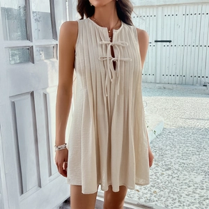 Beige sleeveless pleated mini dress with tie-front detail for summer beach vacation