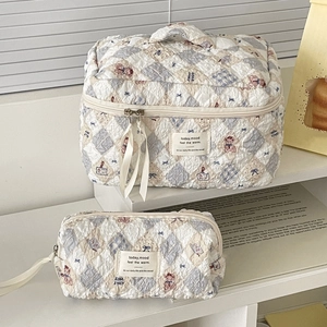 Close-up of quilted bear print cosmetic bags with blue patterns and ribbon details