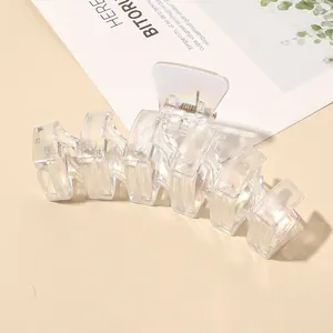 Macro view of transparent iridescent hair claw clip with wavy cut-out design and metal spring