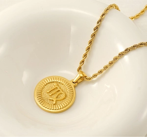 Close-up of 18K gold-plated Virgo zodiac pendant with twisted rope chain in a white bowl