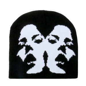 Detailed view of black knitted beanie featuring white jacquard abstract face pattern