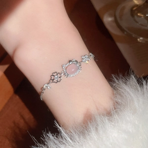 Detailed view of silver heart bracelet with pink gemstone and rhinestone floral links