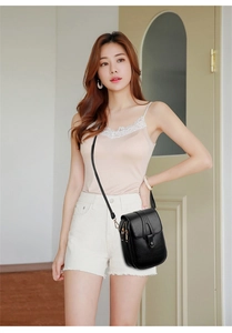 Detail of black lychee grain leather crossbody phone bag with gold zipper and strap