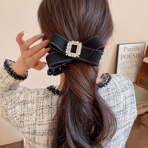 Macro shot of large black fabric bow hair clip with sparkling square rhinestones details