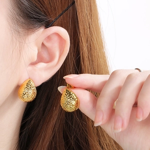 Minimalist gold teardrop earrings with hammered texture shown on model in side profile