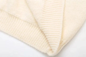Detailansicht des cremefarbenen Strickpullovers mit weicher Rippstruktur und feinem Gewebe