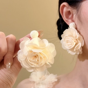 Detail view showing layered cream chiffon flower petals and fabric texture of the earring