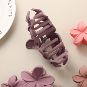 Detailed overhead shot of three matte floral hair claws in purple, pink, and khaki