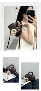 Detail of dark brown glossy embossed Boston bag with twin handles and plush pendant