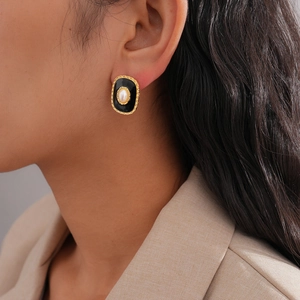 Detail of vintage oval earring with black enamel and pearl inlay worn by a female model