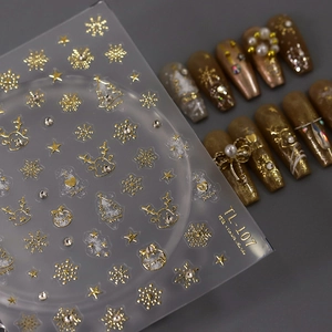 Gold foil Christmas nail stickers with reindeer and snowflake patterns on dark background