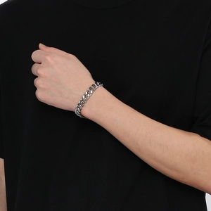 Gros plan d'un bracelet gourmette en argent poli porté au poignet d'un homme