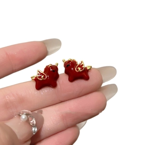 Handheld 18k gold plated red enamel Pegasus stud earrings on a clean white background