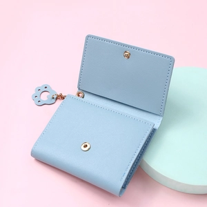 Close-up of blue leather wallet with gold snap button and cute cat paw pendant accessory