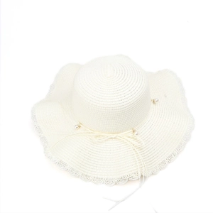 Detailed view of elegant white straw hat featuring pearl accents and a scalloped wavy brim