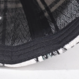 Close-up of black and white plaid baseball cap showing thick tweed texture and neat stitching