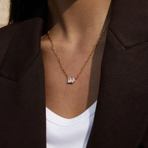 Close-up of gold chain necklace with rectangular and heart-cut clear zircon pendants