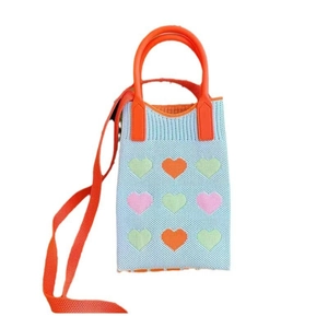 Detail of light blue knit phone bag featuring colorful heart patterns and orange handle
