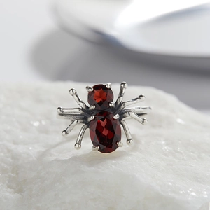Detailed macro view of silver spider ring featuring two red oval garnet gemstones