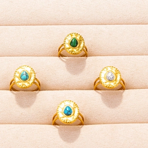 Set of four vintage gold stainless steel rings with teardrop gemstones in a jewelry tray