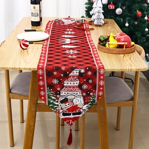 Detail of red and black buffalo plaid Christmas table runner with festive gnome and red tassel