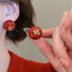 Détail de boucles d'oreilles rouge et or avec caractères chinois de prospérité