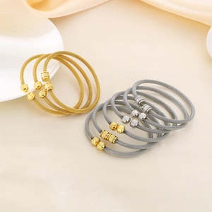 Stacked gold and silver mesh woven open bangles with textured beads on a satin surface