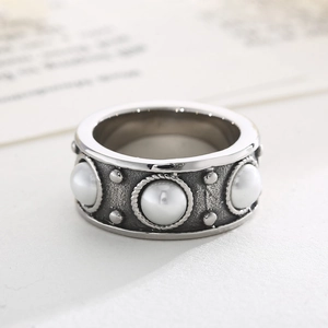 Gros plan d'une bague vintage argentée avec incrustation de perles et détails torsadés