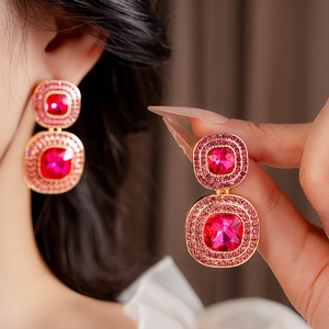 Close-up of vintage gold square earrings with red gemstone and diamond inlay
