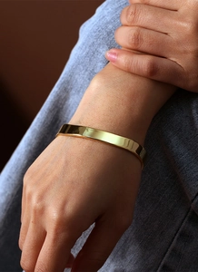 Close-up of minimalist irregular gold plated brass bangle on a female model's wrist