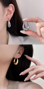 Close-up of geometric C-shaped hoop earrings in polished gold and silver finishes