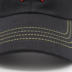 Detail of black cotton baseball cap brim with yellow-green stitching and red embroidery