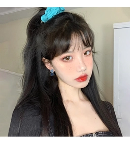 Detailed view of model wearing asymmetric heart drop earrings and blue scrunchie