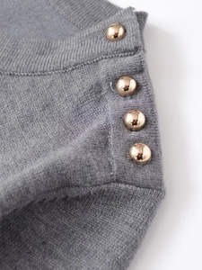Macro shot of grey knit fabric texture featuring decorative golden half-dome metal buttons