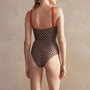 Detail of polka dot swimsuit featuring bold orange contrast straps and a deep U-back cut