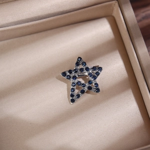 Vista dettagliata della spilla a stella d'argento con strass blu in scatola regalo