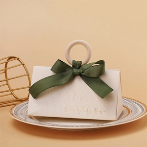Detail of cream wedding favor box with wooden ring handle and green ribbon bow