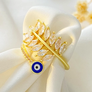 Golden open ring featuring a crystal leaf design and blue evil eye charm on silk