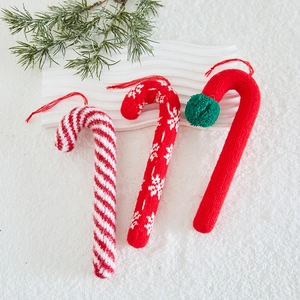 Three knitted Christmas candy cane ornaments with snowflake patterns on festive snow background