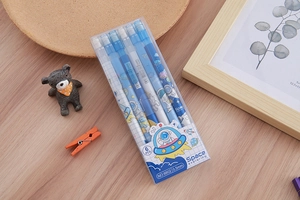Flat lay of six space-themed mechanical pencils in a clear box on a wooden desk