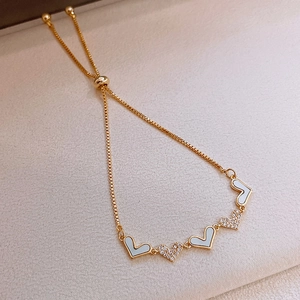 Detail of adjustable gold heart bracelet with sparkling zircon and white shell inserts